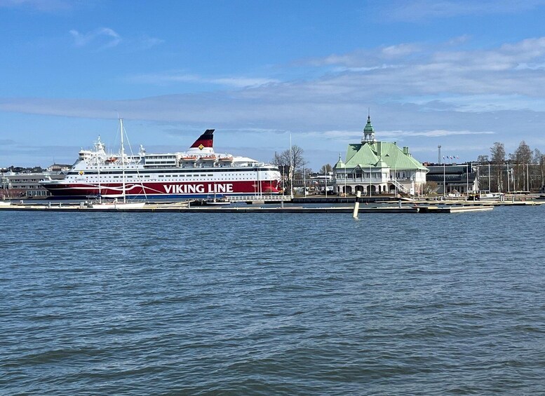 A Viking Line cruise ship docked at a port with a green-roofed building nearby. 2