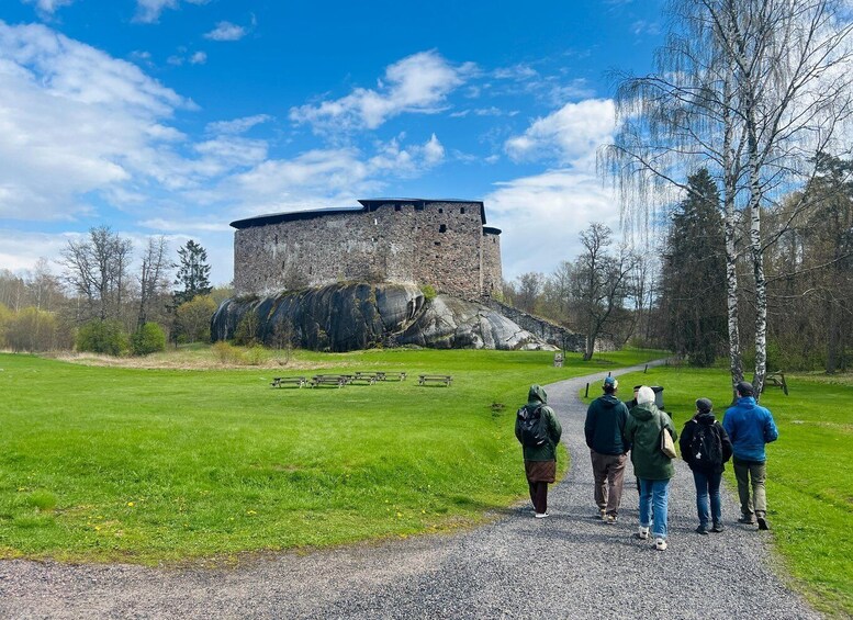 A historic stone tower on a grassy field with a clear sky. 1