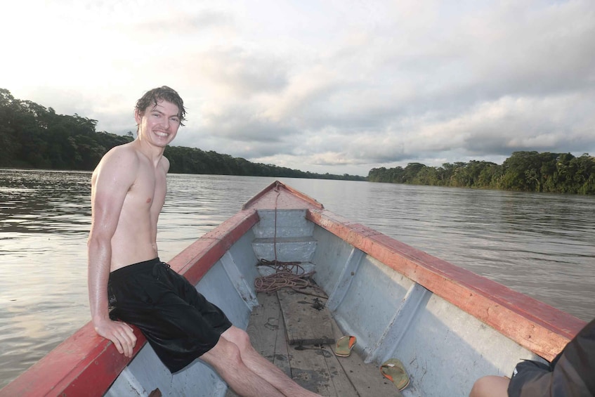 A man in a boat with a red and white interior, sitting on the edge. 1