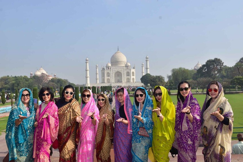 A group of people in traditional attire posing in front of the Taj Mahal. 1