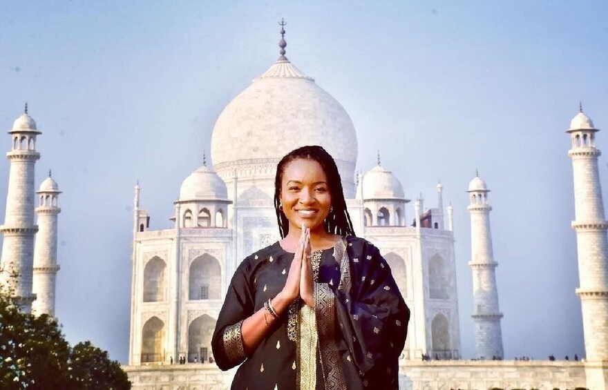 A person in traditional attire standing in front of the Taj Mahal. 2