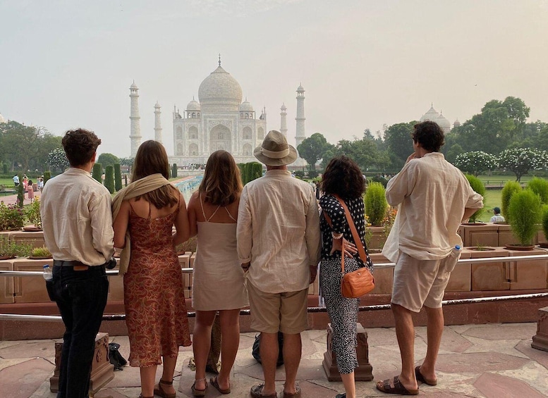 A group of people standing and looking at the Taj Mahal. 1