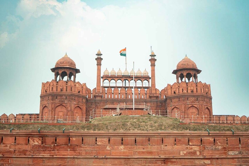 A large, historic building with domed towers and a central archway, featuring the Indian flag. 5