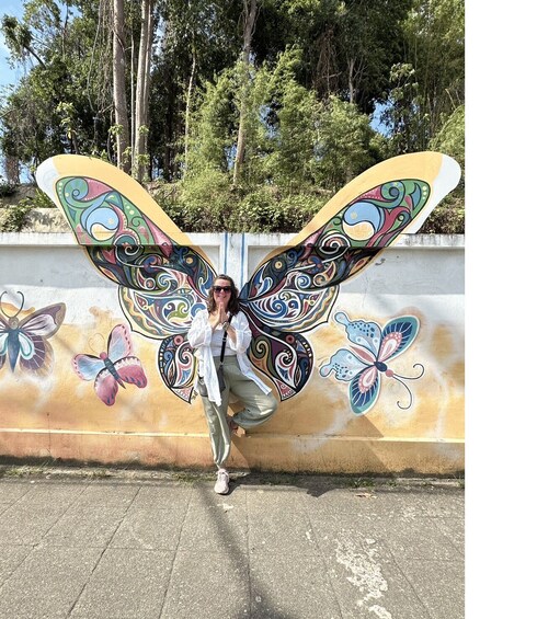 A person standing in front of a wall with colorful butterfly designs. 4
