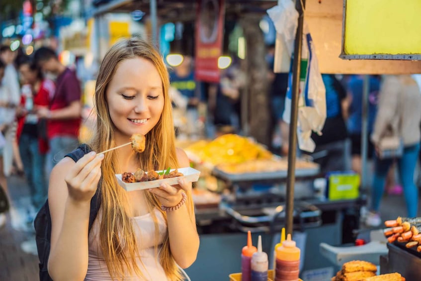 A person eating food at an outdoor market. 1