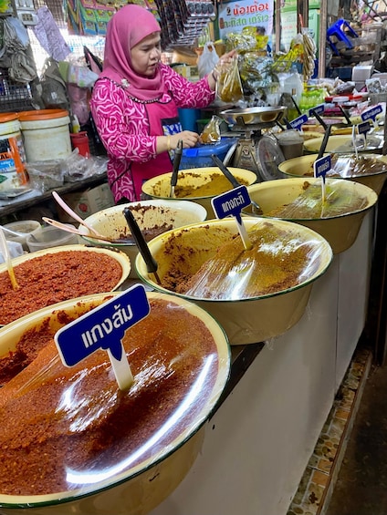 A person serving food at a counter with various dishes labeled in a foreign language. 5
