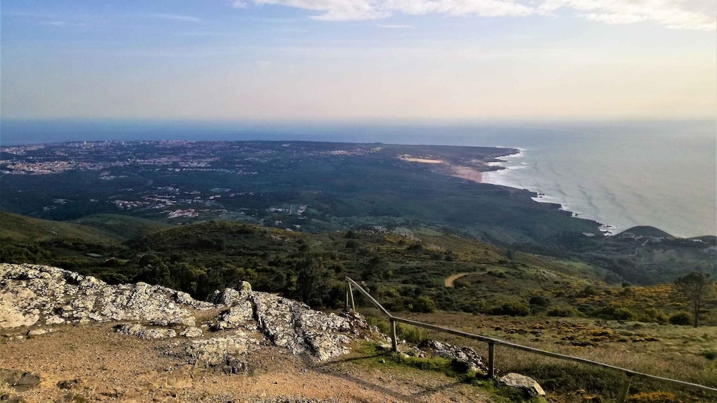 A coastal landscape with a view of the sea, a town in the distance, and rocky terrain. 5