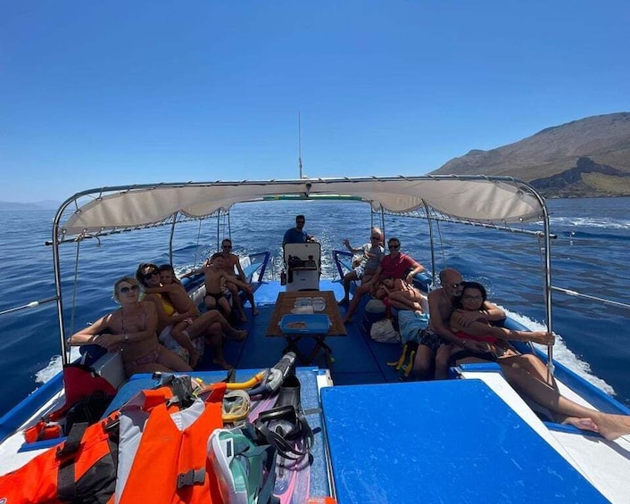 A group of people on a boat with a canopy, surrounded by water and a distant mountain. 5