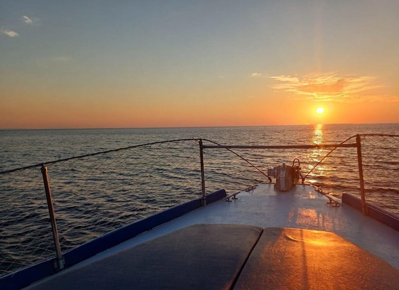 A boat deck at sunset with the sun setting on the horizon. 3