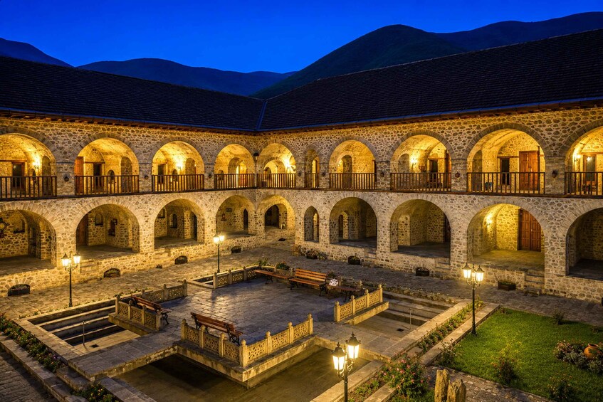 A stone courtyard with arches, benches, and a central fountain. 3