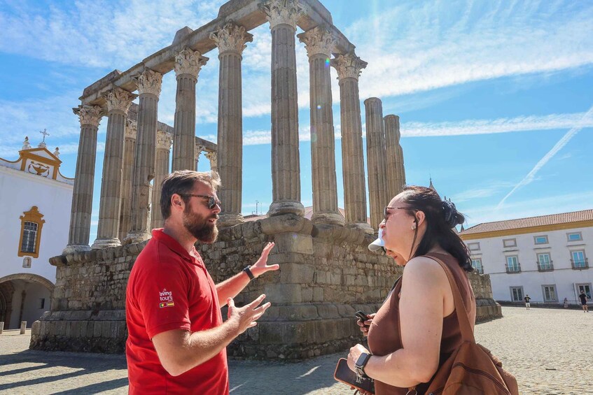 Two people standing in front of ancient Roman columns. 1
