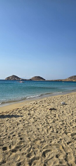 A sandy beach with footprints and a boat in the water. 5