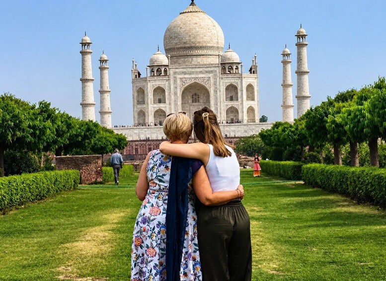 A large white marble mausoleum with four minarets, surrounded by well-maintained greenery and a clear sky. 1