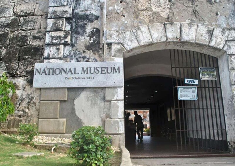 The entrance to the National Museum in Zamboanga City, featuring a stone archway and a sign indicating the museum is open. 2