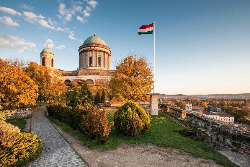 A historic building with domed architecture, a flag, and a stone wall. 5