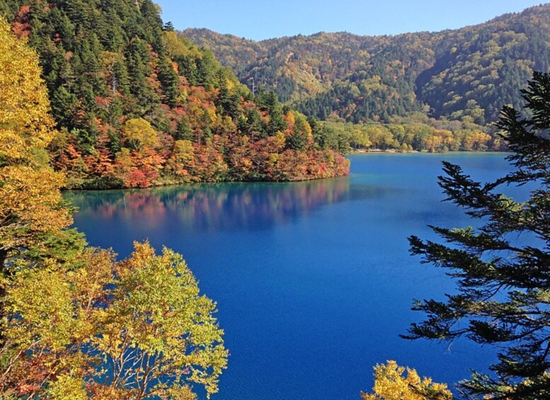A calm lake surrounded by autumn-colored trees and hills. 1