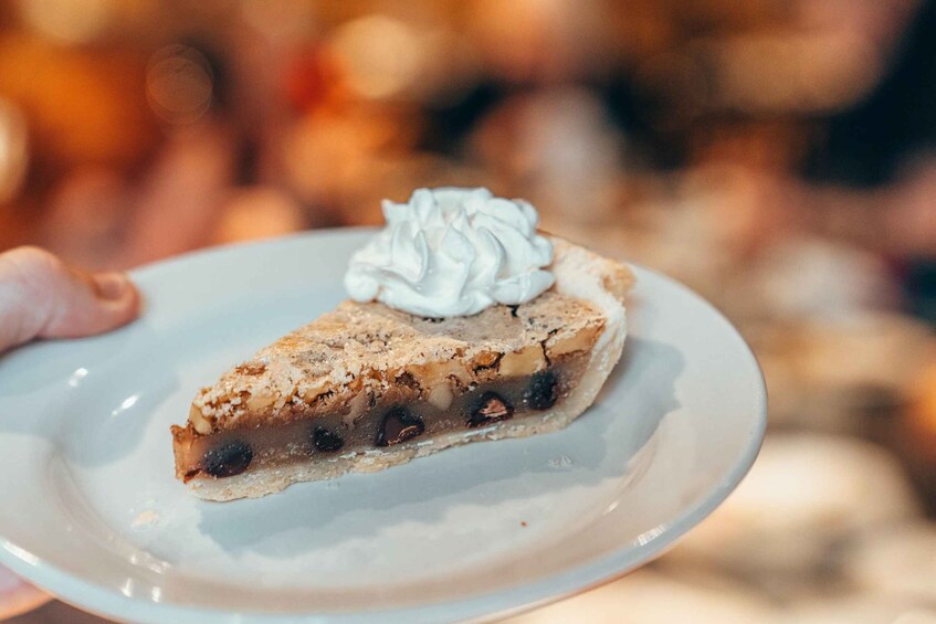 A slice of pie with a crumbly crust, a layer of fruit, and a dollop of whipped cream on top. 1