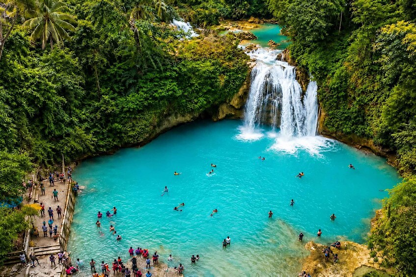 A waterfall cascading into a turquoise pool surrounded by lush greenery. 2