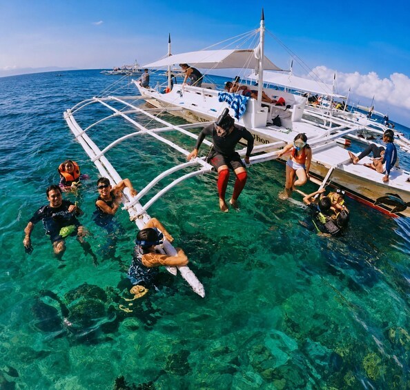 People snorkeling and swimming in clear blue water around a boat. 3