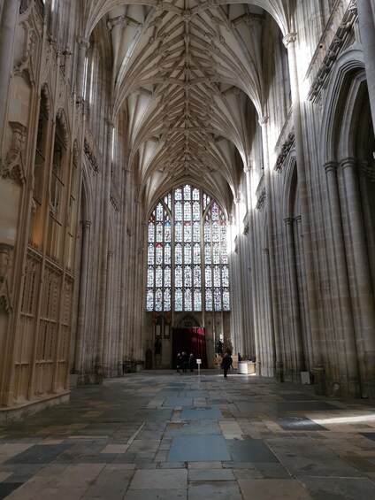 A cathedral interior with high vaulted ceilings, large stained glass windows, and stone columns. 5