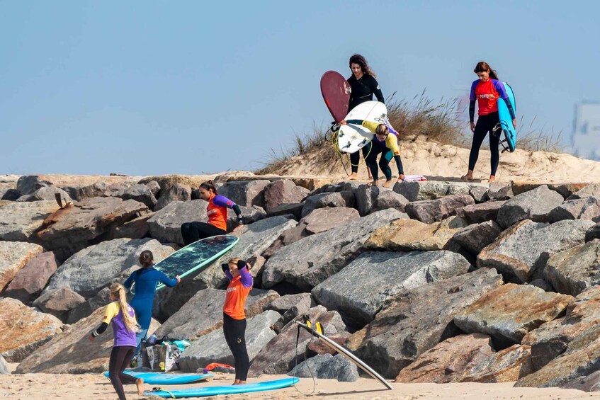People on a rocky beach with surfboards. 5