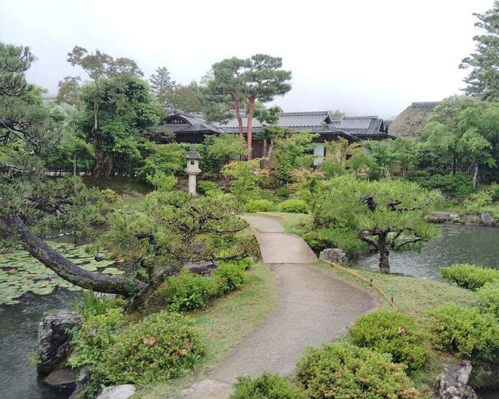 A traditional Japanese garden with a stone path, water features, and various trees. 5