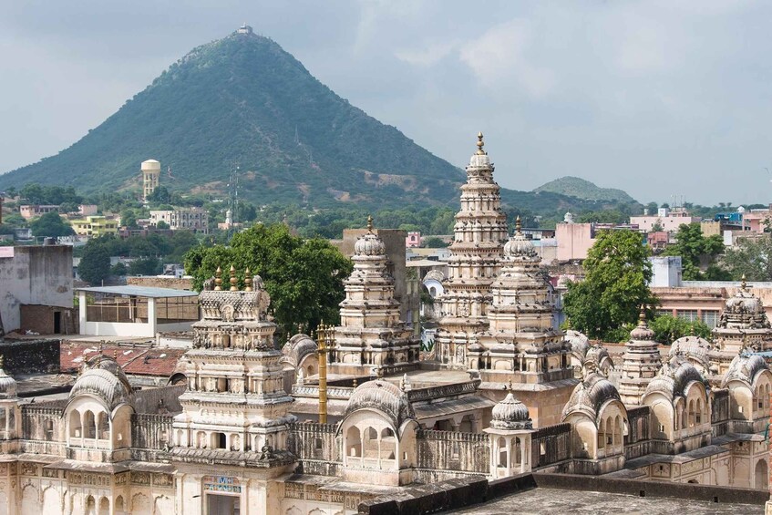 A temple complex with multiple spires, a water tower, and a hill in the background. 5