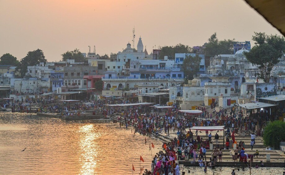A crowded riverside with people and buildings in the background. 3