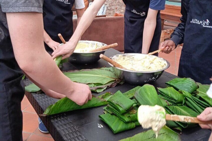 People preparing food with leaves on a table. 1