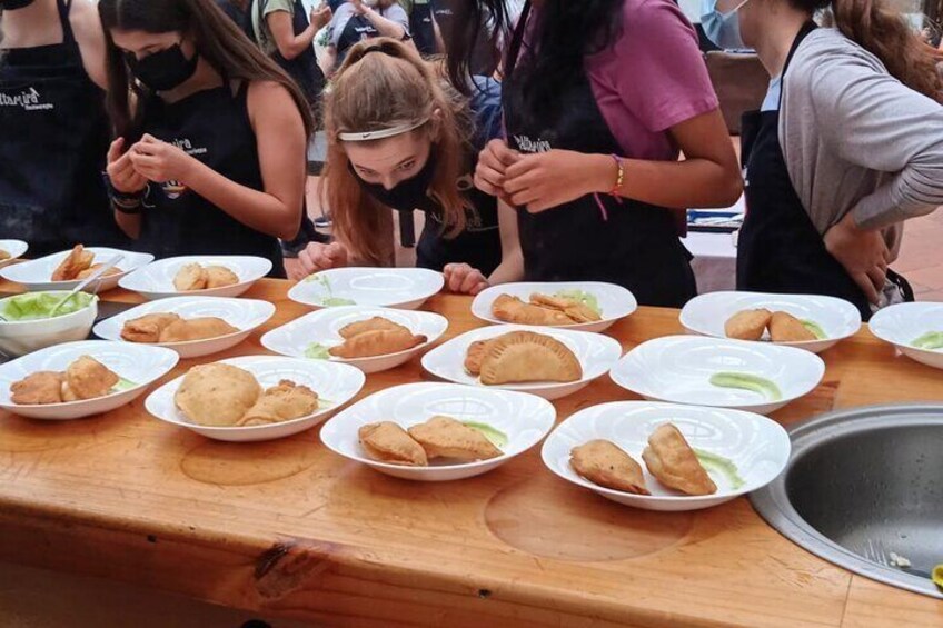 A group of people preparing food at a table with plates of food. 4