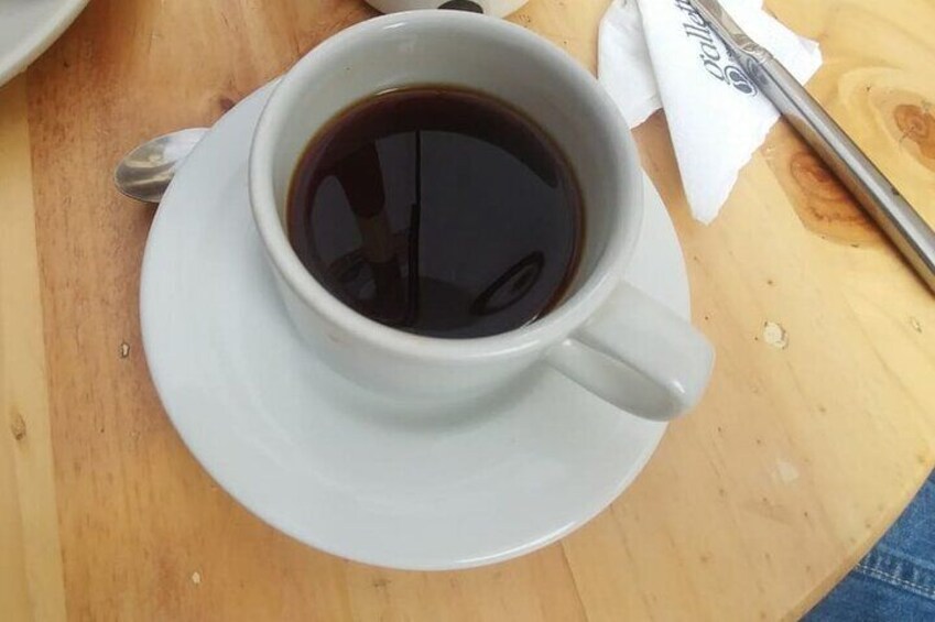 A white cup of coffee on a saucer on a wooden table. 3