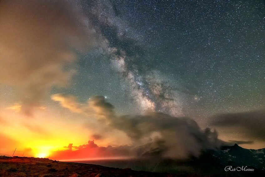 A starry night sky over a mountainous landscape with a sunset. 4