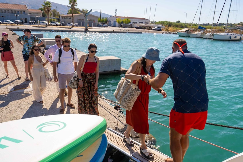 Un grupo de personas en un muelle junto a un puerto deportivo, con barcos y edificios al fondo. 4