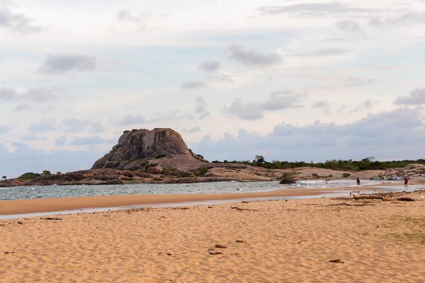 A sandy beach with a prominent rock formation in the background. 4