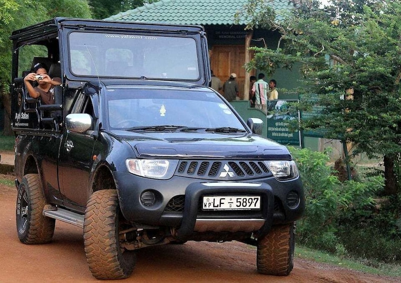 A black SUV with a roof rack parked on a dirt road. 2