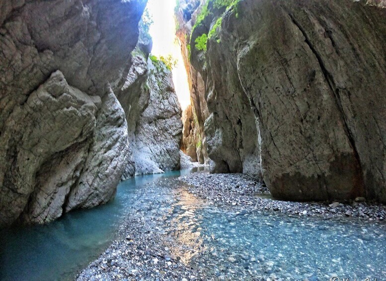 A narrow canyon with a stream flowing through it. 3