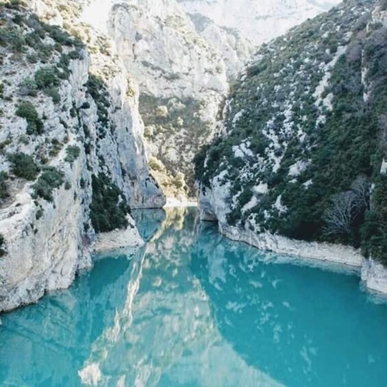 A turquoise lake surrounded by rocky cliffs and sparse vegetation. 1