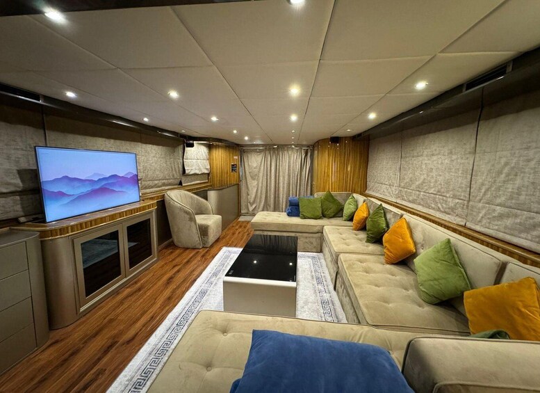 A modern living room with a flat-screen TV, a sofa with colorful cushions, a wooden floor, and a patterned rug. 5
