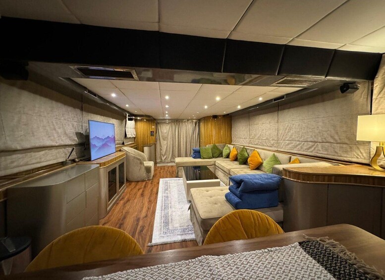 A modern interior with a sofa, cushions, a TV, and a lamp. 2
