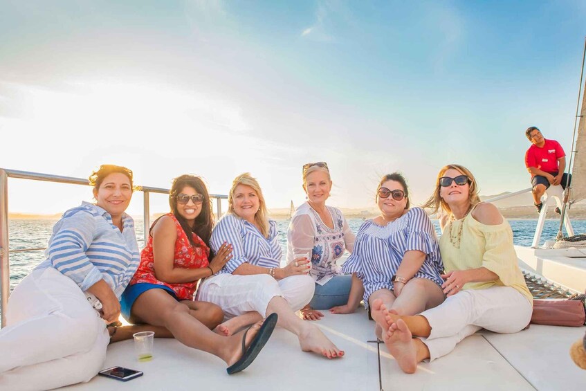 A group of people sitting on a boat deck with a body of water and a distant shoreline in the background. 5