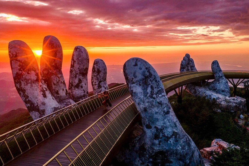 A bridge with a unique hand-shaped design, overlooking a scenic sunset view. 1