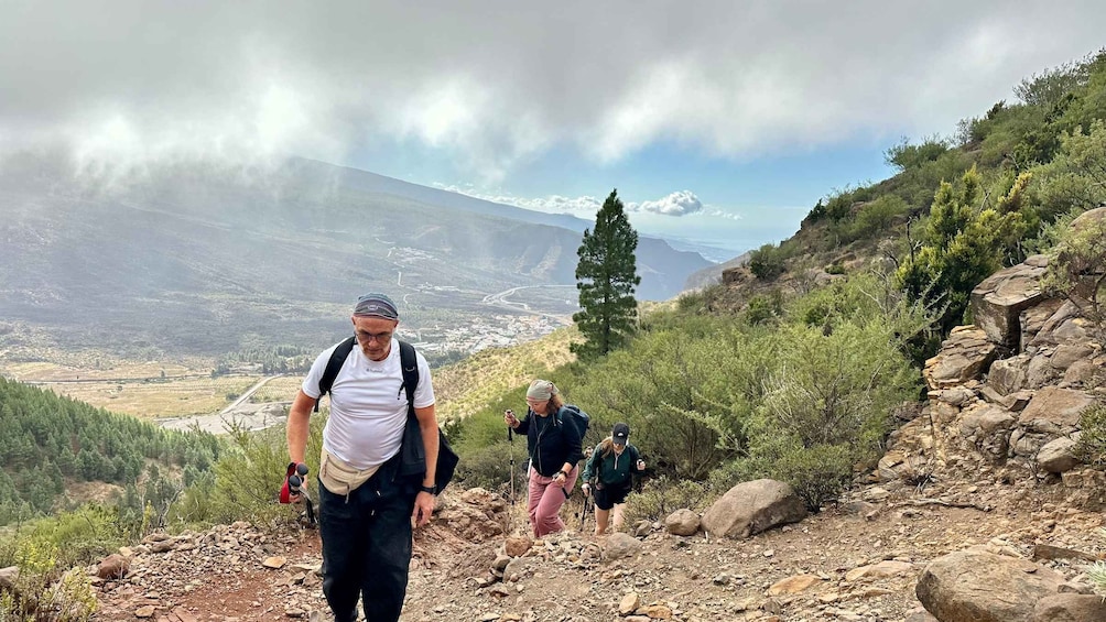 Hikers on a rocky trail with a mountainous landscape in the background. 2