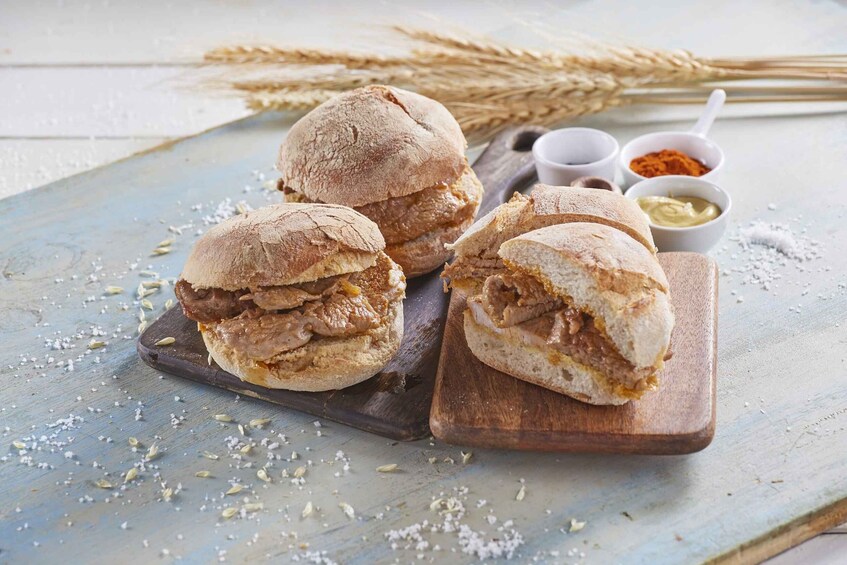 Three sandwiches on wooden boards with wheat in the background. 2