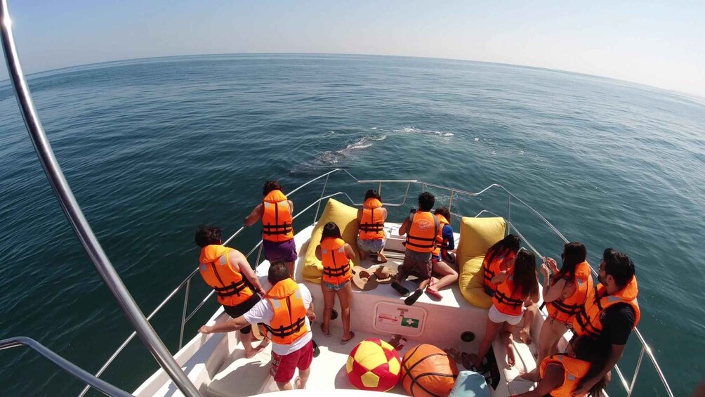 A group of people on a boat wearing life jackets, with a clear view of the ocean. 5