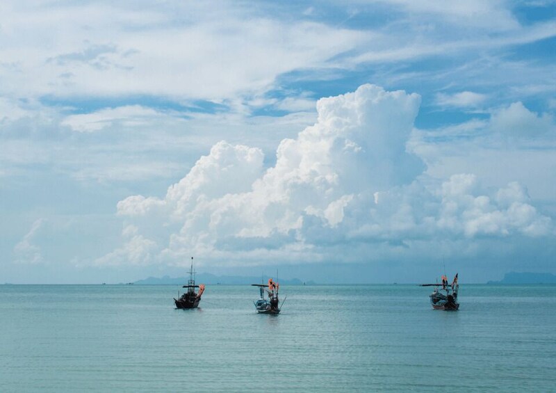 Three boats on calm sea water with a large cloud in the sky. 4