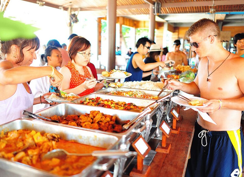 A buffet line with various dishes and a person serving food. 2