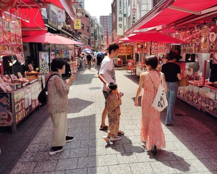 A bustling street market with red canopies and various stalls. 1