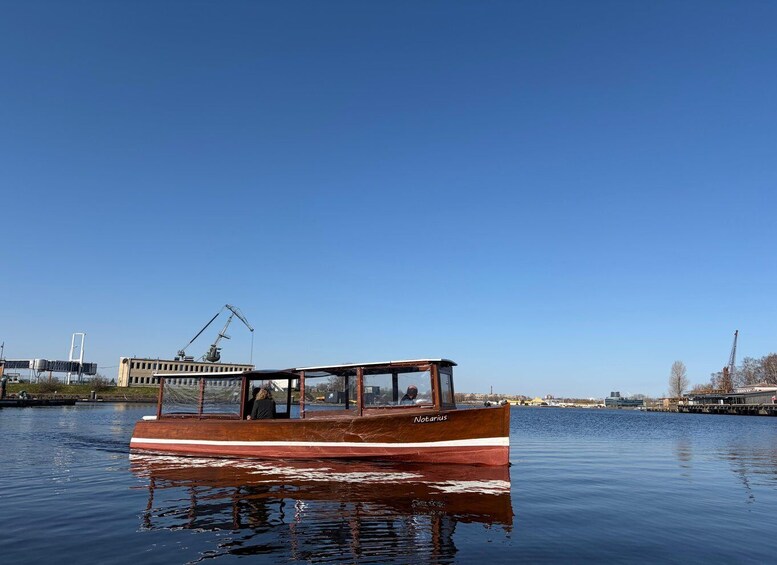 A wooden boat named 'Notarius' on calm water with a clear sky. 1