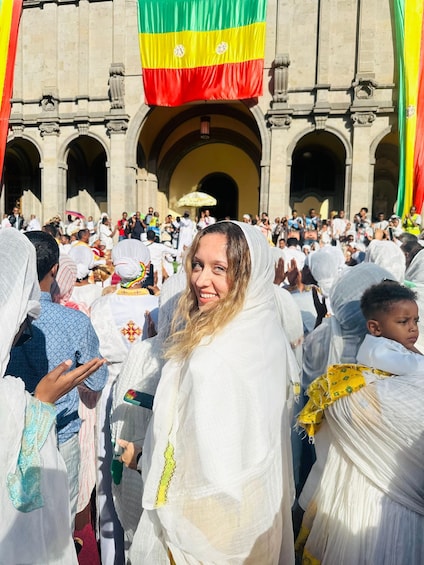 A crowd of people in traditional attire in front of a building with arches and a flag. 5