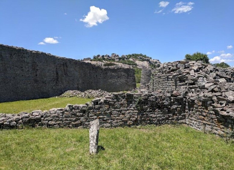 Ancient stone ruins with a grassy foreground and a clear blue sky. 5